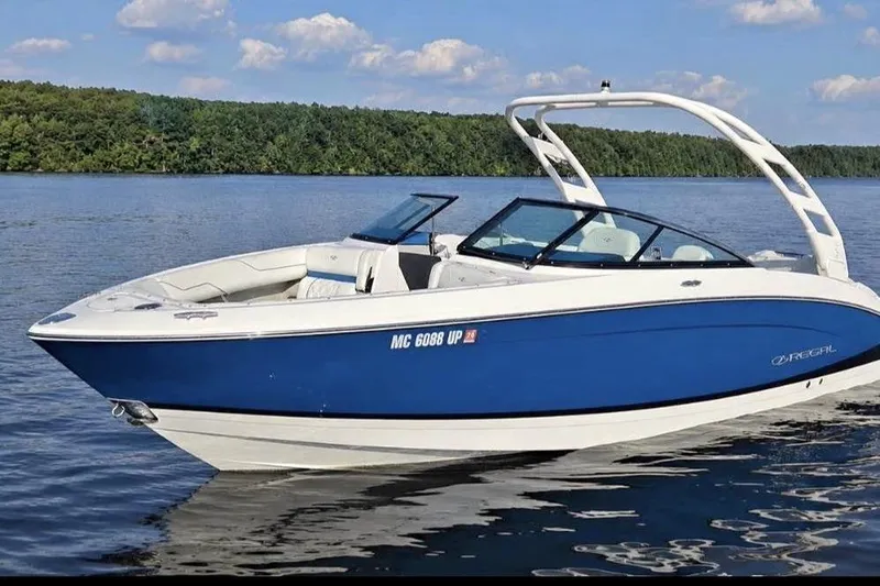 Slide: The Image of 2021 Regal LS4 Surf boat on a serene lake with lush green shoreline. - 22