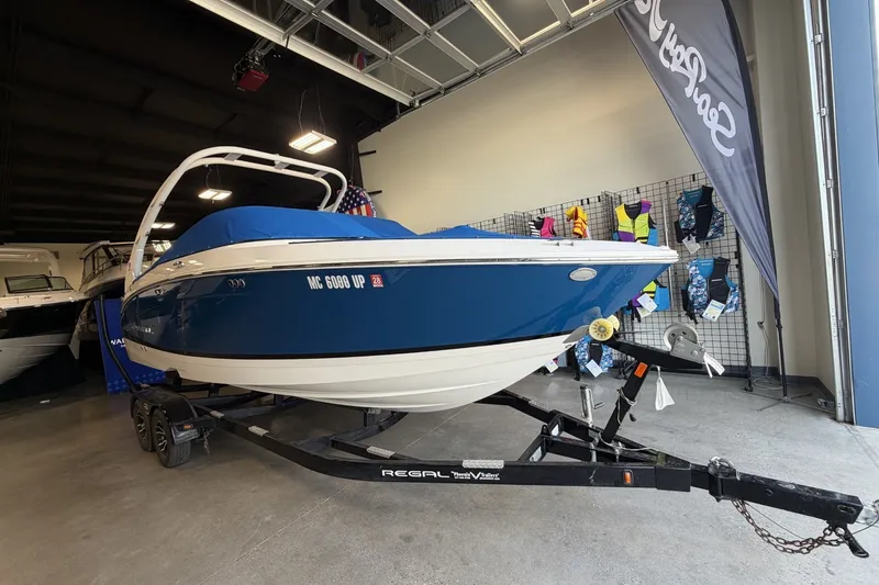 Slide: The Image of 2021 Regal LS4 Surf boat in showroom, blue and white design, on trailer. - 6