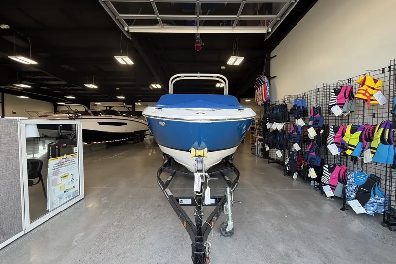 Slide: The Image of 2021 Regal LS4 Surf boat displayed in showroom with life jackets on racks. - 7
