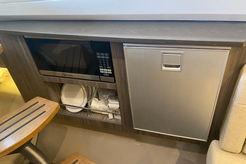 Slide: The Image of 2019 Sea Ray SLX 400 interior with microwave, fridge, and storage space. - 52