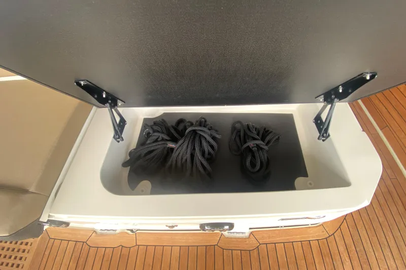 Slide: The Image of Storage compartment on 2019 Sea Ray SLX 400 boat with coiled black ropes. - 13