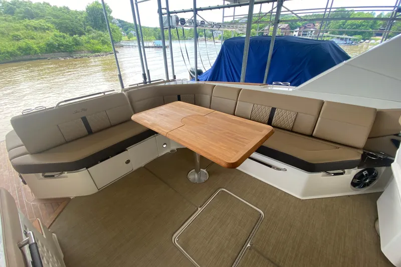 Slide: The Image of 2019 Sea Ray SLX 400 boat interior with beige seating and wooden table. - 16