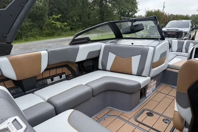 Slide: The Image of 2022 Malibu Wakesetter 23 MXZ boat interior with gray and tan seating, parked outdoors. - 13