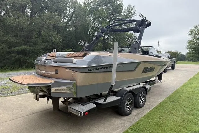 Slide: The Image of 2022 Malibu Wakesetter 23 MXZ boat on trailer, parked on driveway, surrounded by greenery. - 3