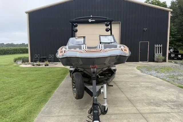 Slide: The Image of 2022 Malibu Wakesetter 23 MXZ on trailer, parked in front of a large garage. - 6
