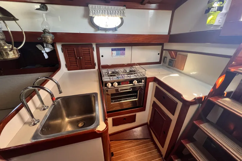 Slide: The Image of 1977 Alajuela 38 MKI yacht kitchen with stove, sink, and wooden cabinetry. - 38