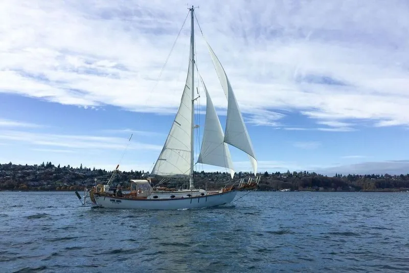 The Image of Sailing yacht Alajuela 38 MKI 1977 on a serene lake under a partly cloudy sky. - 0