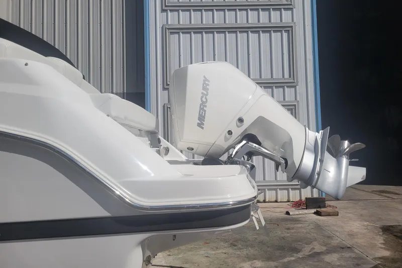 Slide: The Image of 2022 Four Winns HD3 boat with Mercury outboard motor, parked near a metal building. - 9