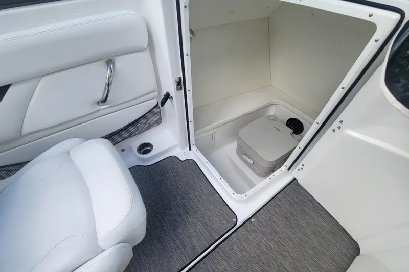 Slide: The Image of 2022 Four Winns HD3 boat interior with compact toilet and seating area. - 23
