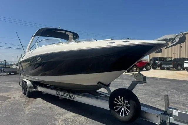 The Image of 2004 Monterey 298SS Super Sport boat on trailer, parked outdoors under clear blue sky. - 0
