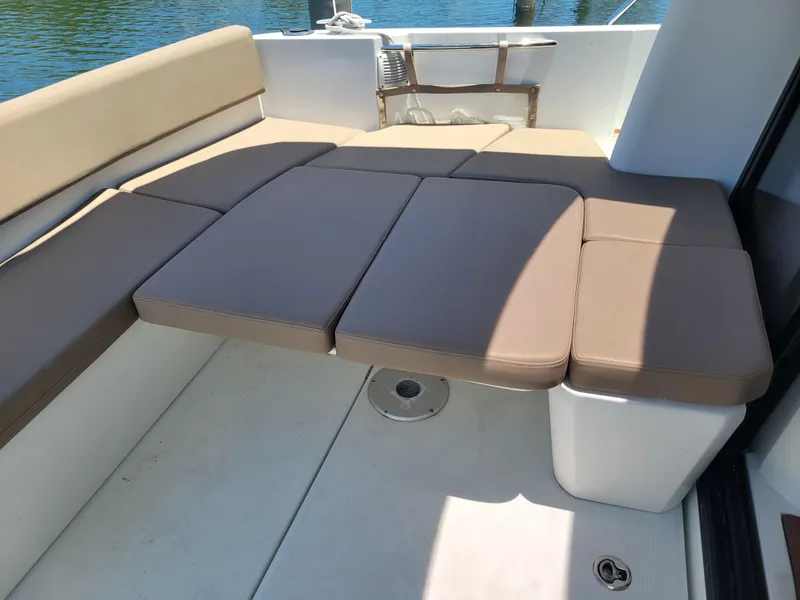 Slide: The Image of 2016 Jeanneau Merry Fisher 855 boat seating area with beige cushions. - 9