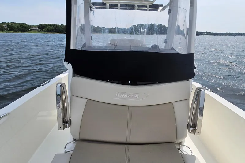 Slide: The Image of 2021 Boston Whaler 270 Dauntless boat on water, featuring helm seating and clear enclosure. - 14