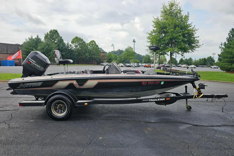 Slide: The Image of 1994 Nitro 180 FS boat on trailer, parked outdoors, with trees and parking lot in background. - 4