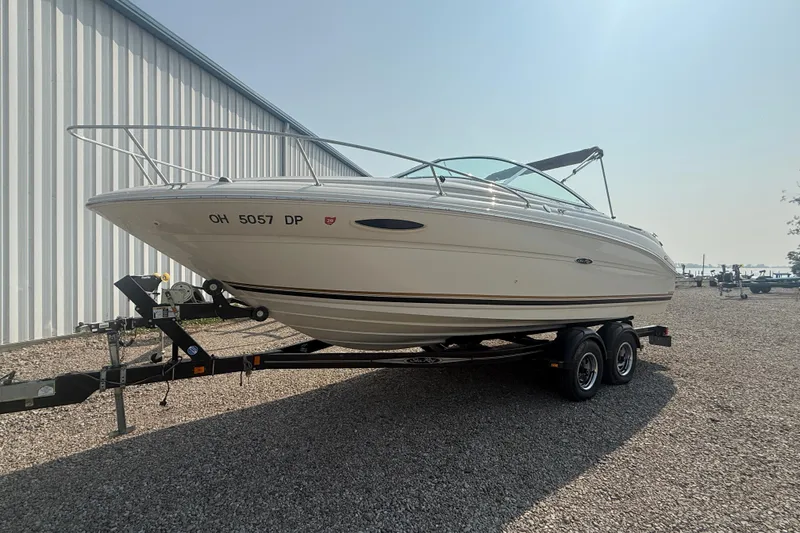 Slide: The Image of 2003 Sea Ray 225 Weekender boat on trailer, parked outdoors near a metal building. - 1