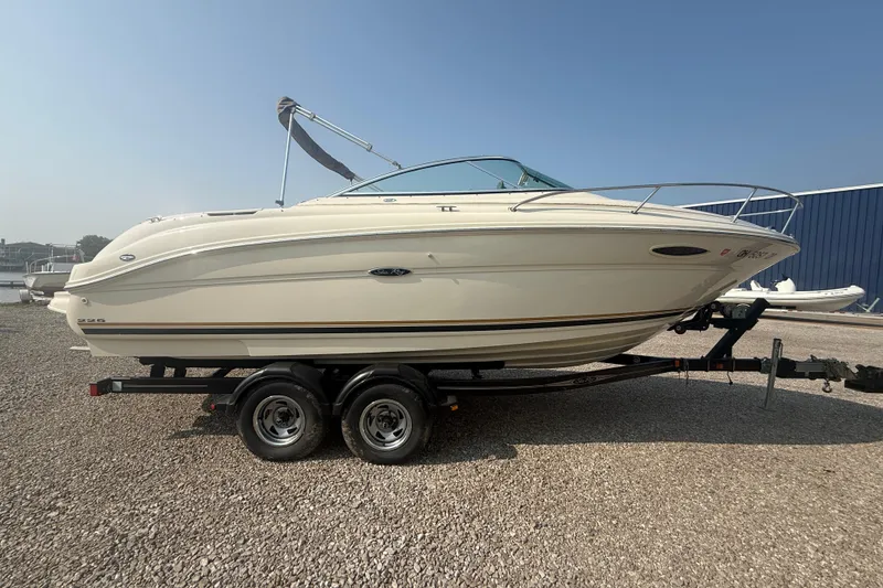 The Image of 2003 Sea Ray 225 Weekender boat on trailer, side view, parked on gravel. - 0