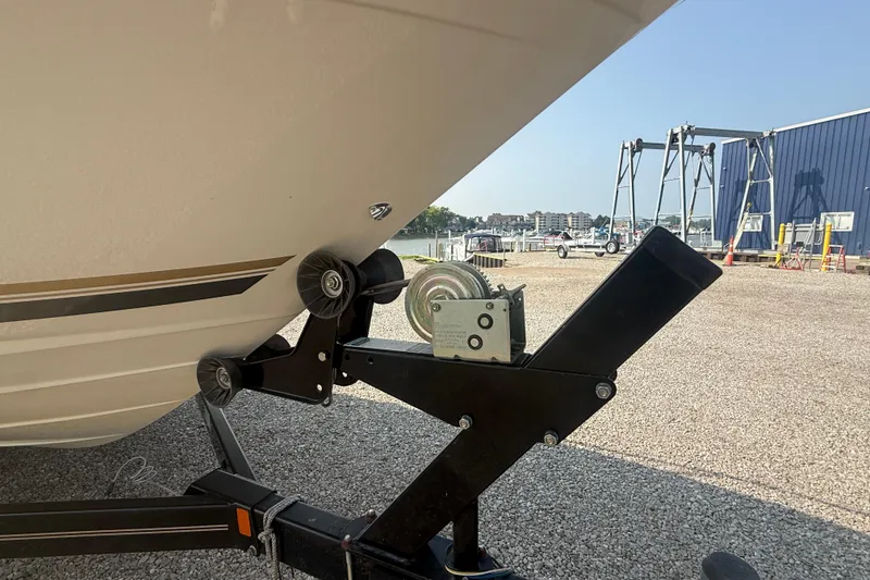 Slide: The Image of 2003 Sea Ray 225 Weekender boat on trailer, parked in marina with clear sky. - 4