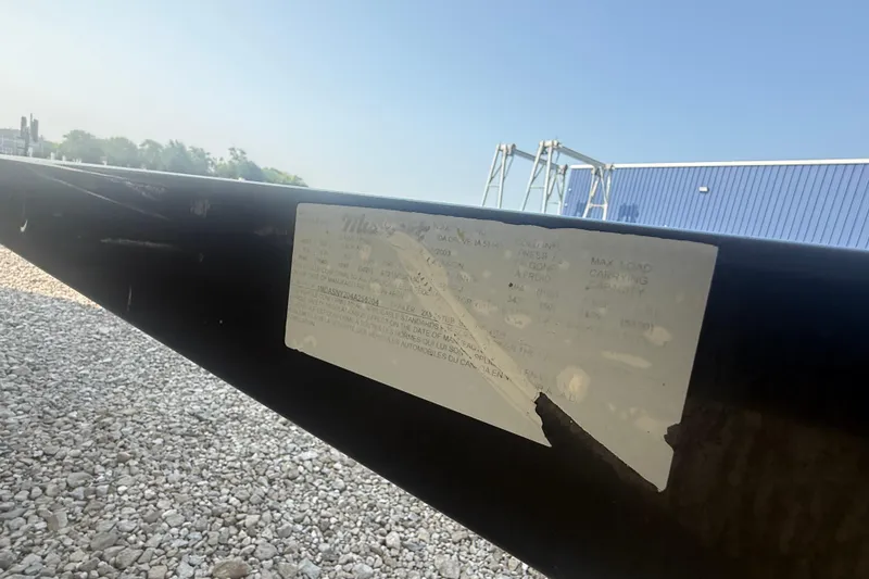 Slide: The Image of 2003 Sea Ray 225 Weekender trailer label on black metal beam, outdoor setting. - 6