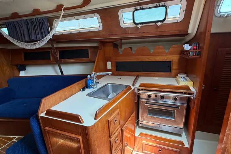 Slide: The Image of 1986 Pearson 33 yacht interior with wooden cabinetry, compact kitchen, and cozy seating area. - 6
