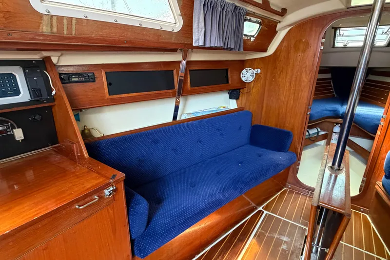 Slide: The Image of Interior of a 1986 Pearson 33 sailboat with blue seating and wooden finishes. - 7
