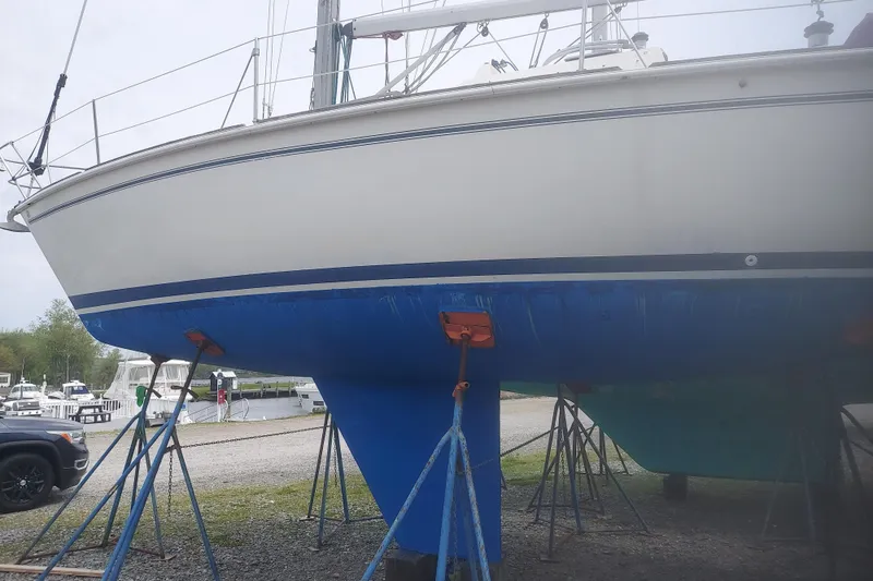 Slide: The Image of 1986 Pearson 33 sailboat on stands, blue hull, marina background. - 42