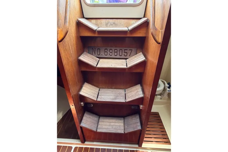Slide: The Image of Wooden steps inside a 1986 Pearson 33 sailboat, showcasing registration number 698057. - 13