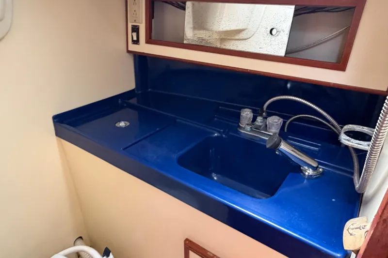 Slide: The Image of Blue sink area in a 1986 Pearson 33 yacht, featuring a mirror and faucet. - 11
