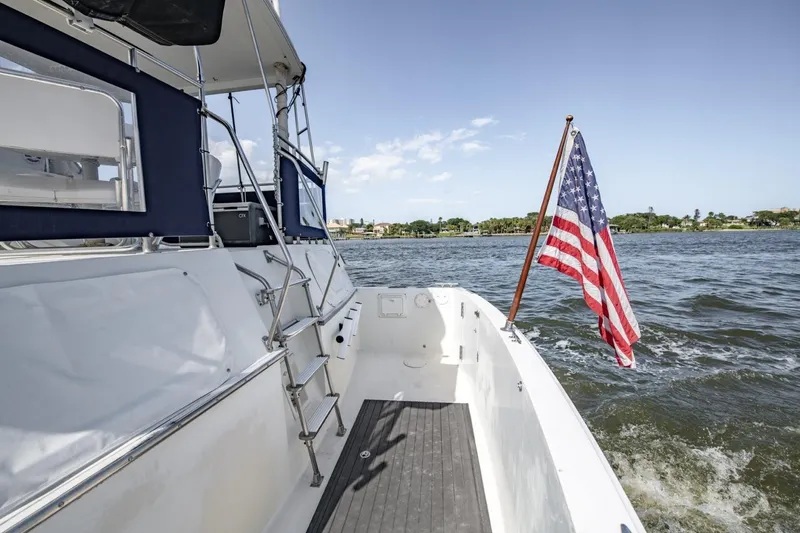 Slide: The Image of 1988 Tollycraft 44 Cockpit Motor Yacht with American flag on open water. - 44