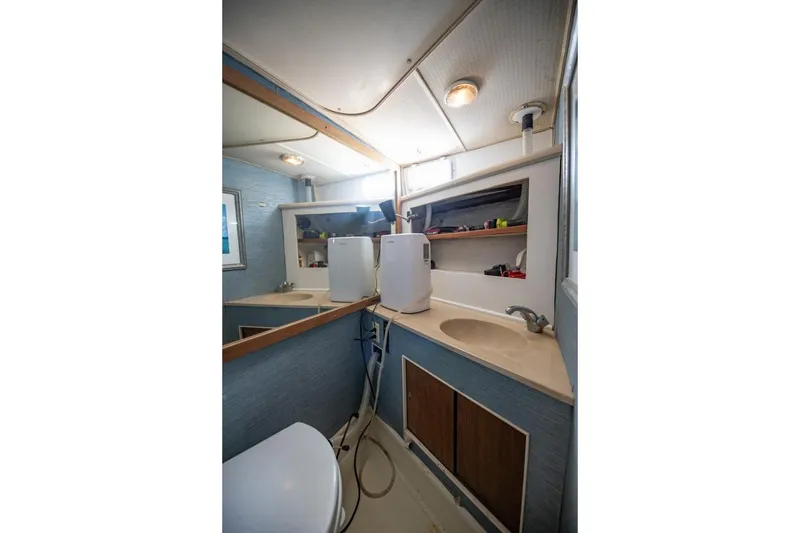 Slide: The Image of 1988 Tollycraft 44 Cockpit Motor Yacht bathroom with sink, mirror, and storage shelves. - 34