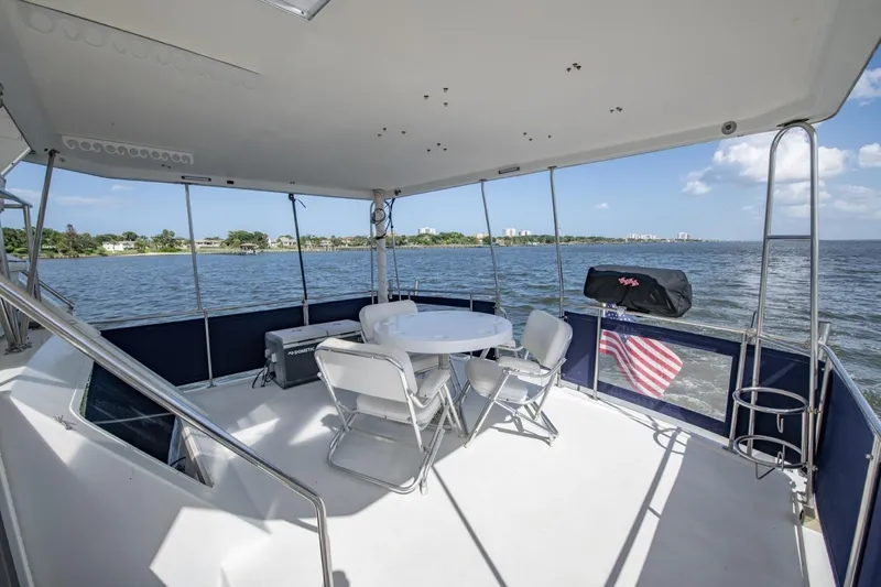 Slide: The Image of 1988 Tollycraft 44 Cockpit Motor Yacht deck with seating, ocean view, and American flag. - 37