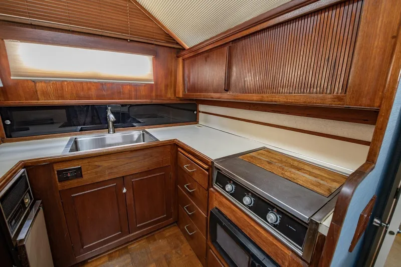 Slide: The Image of 1988 Tollycraft 44 Cockpit Motor Yacht kitchen with wood cabinetry and stainless steel sink. - 24