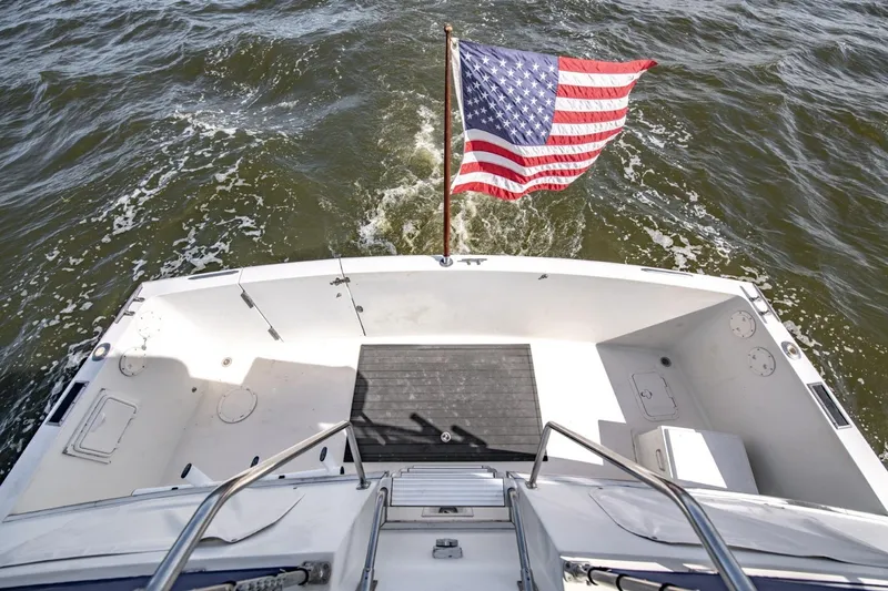 Slide: The Image of 1988 Tollycraft 44 Cockpit Motor Yacht with American flag on open water. - 41