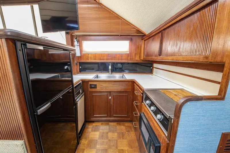 Slide: The Image of 1988 Tollycraft 44 Cockpit Motor Yacht kitchen with wood cabinetry and modern appliances. - 22