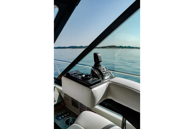 Slide: The Image of Interior view of 2020 Tiara Yachts C49 Coupe helm with joystick control, overlooking calm waters. - 25