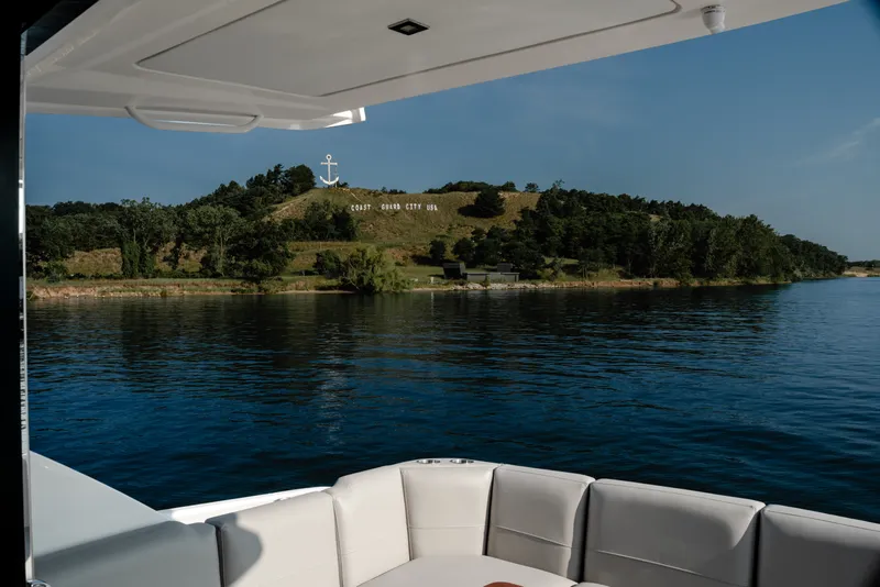 Slide: The Image of 2020 Tiara Yachts C49 Coupe on serene water near lush green hillside. - 14