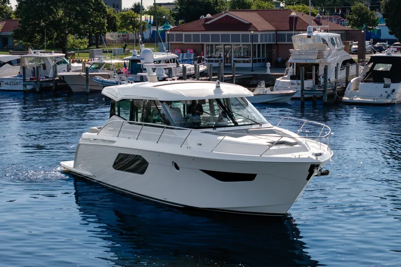 Slide: The Image of 2020 Tiara Yachts C49 Coupe cruising in a marina, surrounded by other boats. - 4