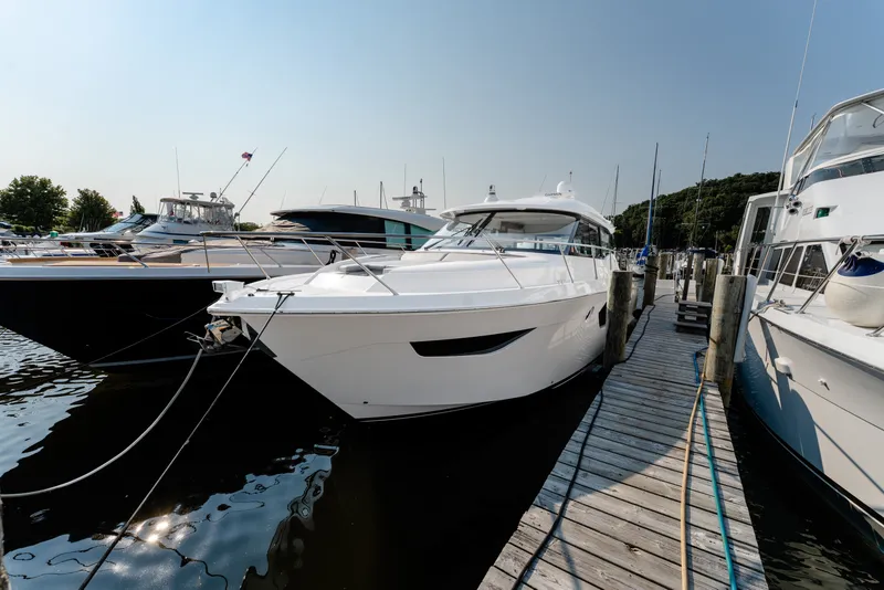 Slide: The Image of 2020 Tiara Yachts C49 Coupe docked at marina, surrounded by other boats. - 10