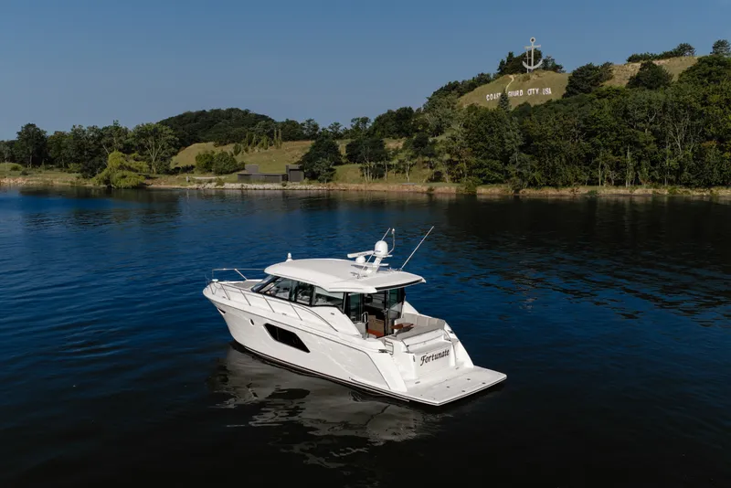 Slide: The Image of 2020 Tiara Yachts C49 Coupe on serene water near wooded shoreline. - 2
