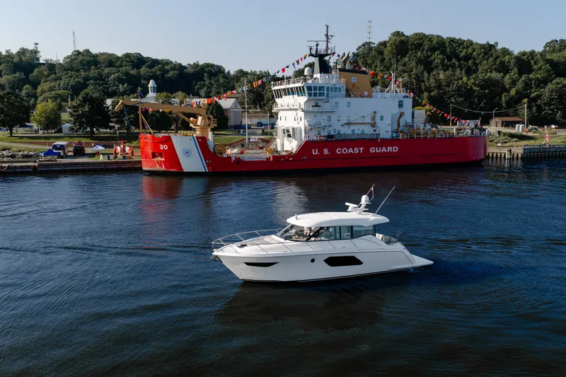 Slide: The Image of 2020 Tiara Yachts C49 Coupe cruising near a U.S. Coast Guard ship. - 0