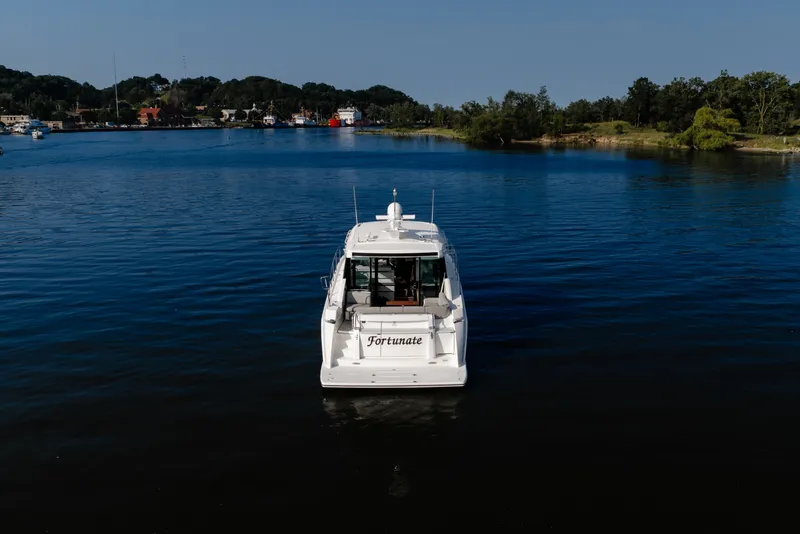 Slide: The Image of 2020 Tiara Yachts C49 Coupe on serene water, distant shoreline view. - 3