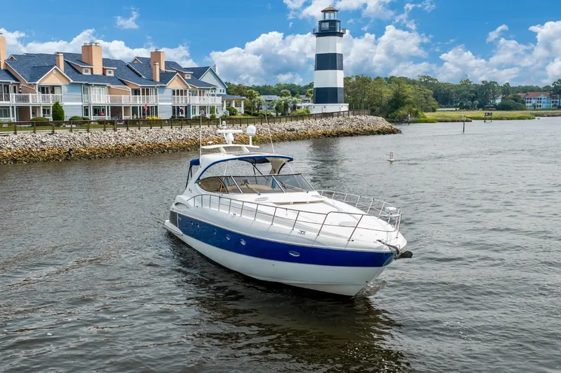 Slide: The Image of 2003 Cruisers 5470 Express yacht near a lighthouse and waterfront homes. - 20