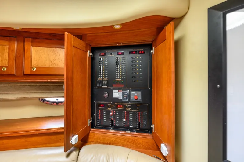 Slide: The Image of Electrical panel inside 2003 Cruisers 5470 Express yacht, featuring wooden cabinetry. - 41