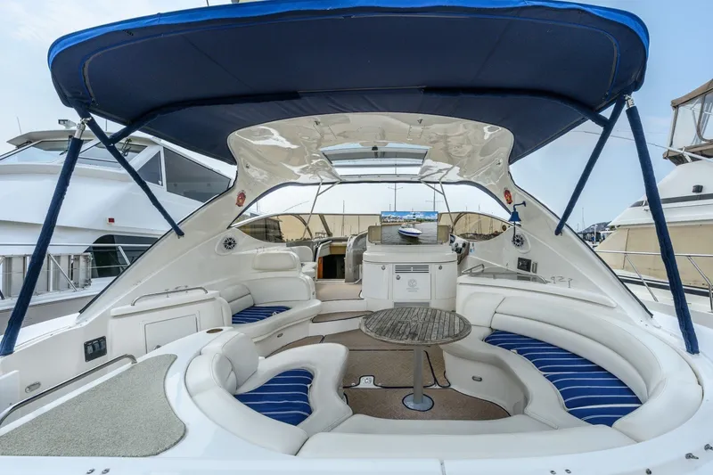 Slide: The Image of 2003 Cruisers 5470 Express yacht interior with seating and table under blue canopy. - 23