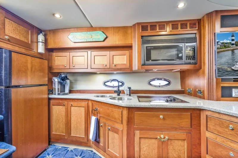 Slide: The Image of Luxurious 2003 Cruisers 5470 Express yacht kitchen with wood cabinetry and modern appliances. - 54