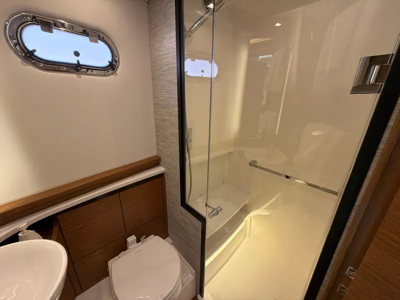 Slide: The Image of The image shows a modern yacht bathroom with a shower, toilet, and porthole. - 34