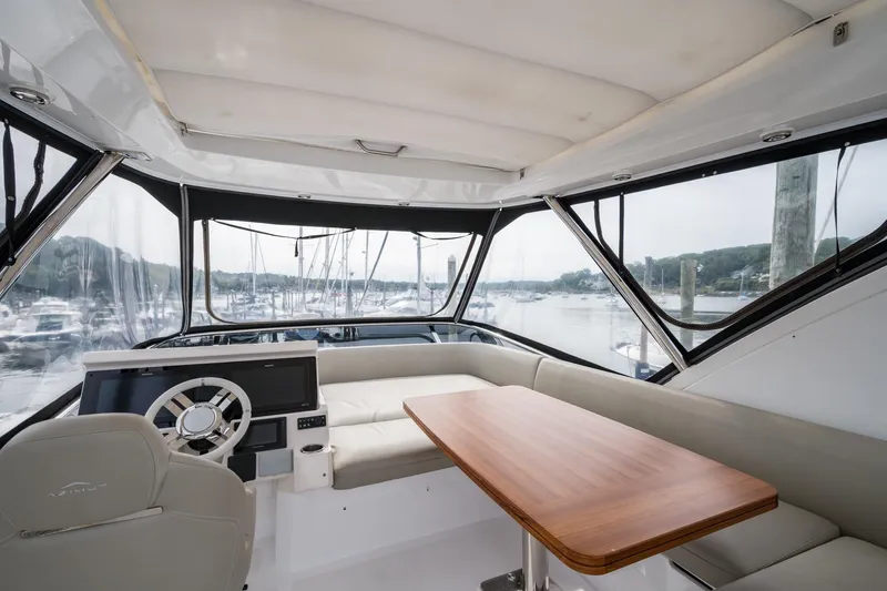 Slide: The Image of 2020 Azimut Fly 50 yacht interior with helm, seating, and table, overlooking marina. - 35