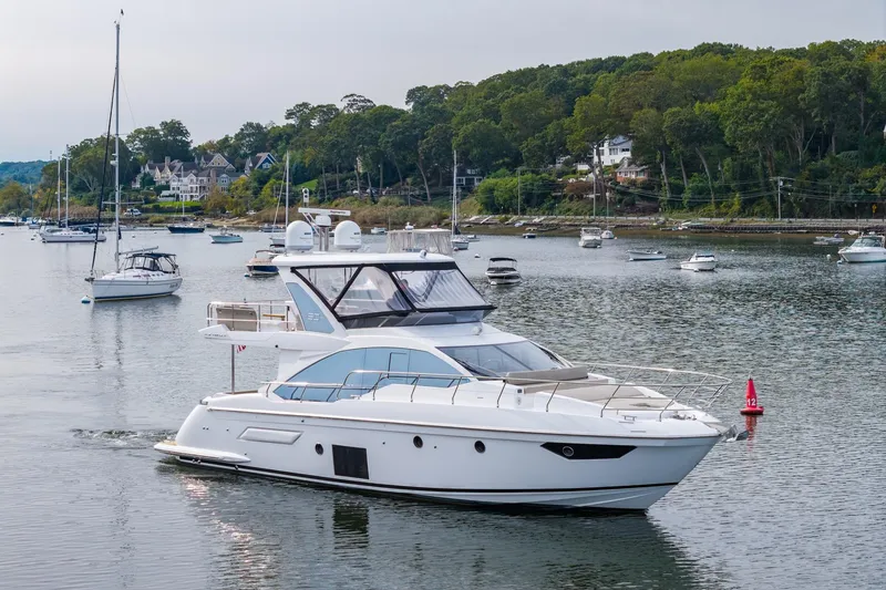 Slide: The Image of 2020 Azimut Fly 50 yacht cruising in a scenic harbor with lush greenery. - 6