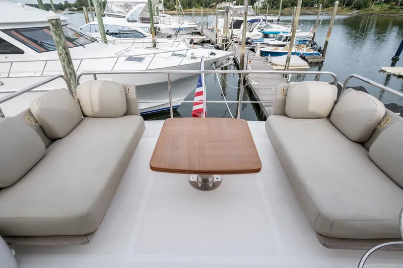 Slide: The Image of Azimut Fly 50 yacht deck with beige seating and wooden table, docked at marina. - 33