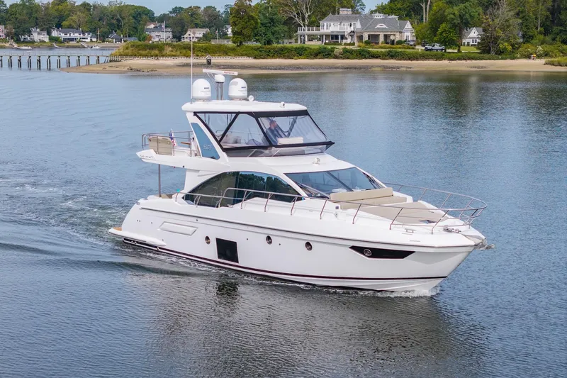 Slide: The Image of 2020 Azimut Fly 50 yacht cruising on a serene waterway near luxury homes. - 4