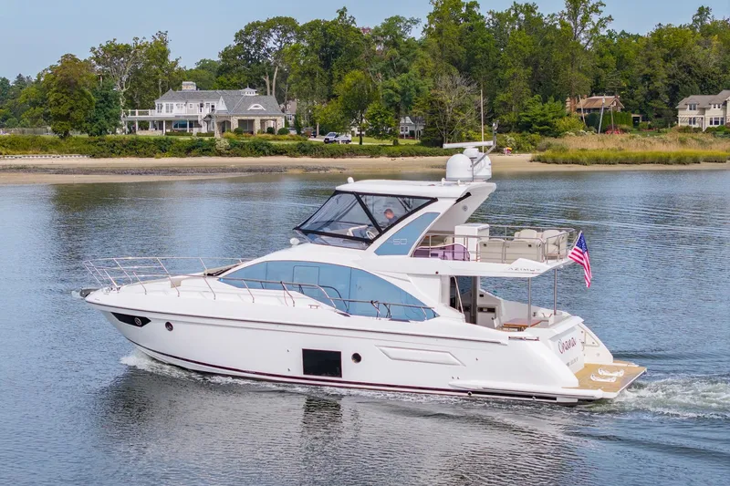 Slide: The Image of 2020 Azimut Fly 50 yacht cruising on a serene lake with lush greenery in the background. - 16