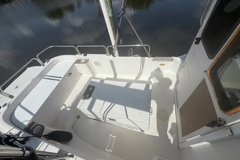 Slide: The Image of 2012 Ranger Tugs R-21 EC boat deck with seating, docked by calm water. - 5